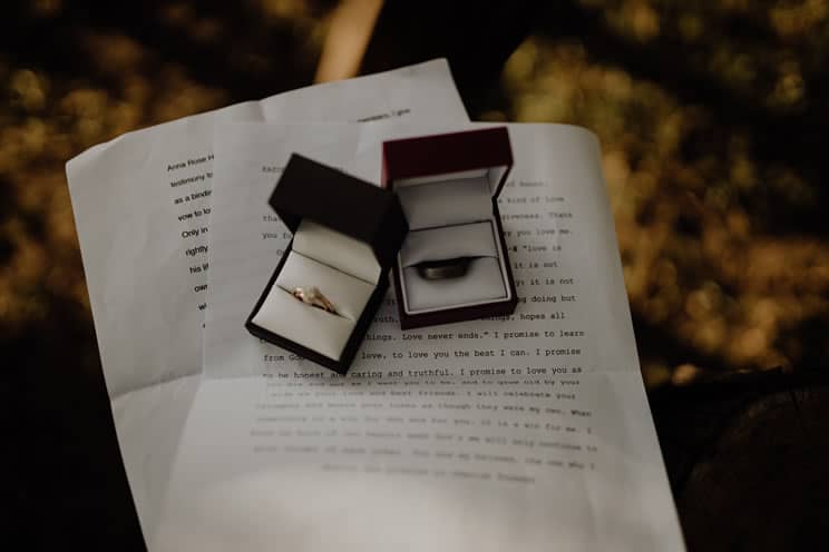 Wedding vows on paper with two ring boxes and rings on top