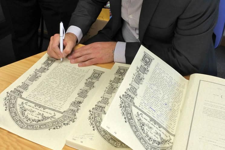 Jewish groom signing legal document at the wedding