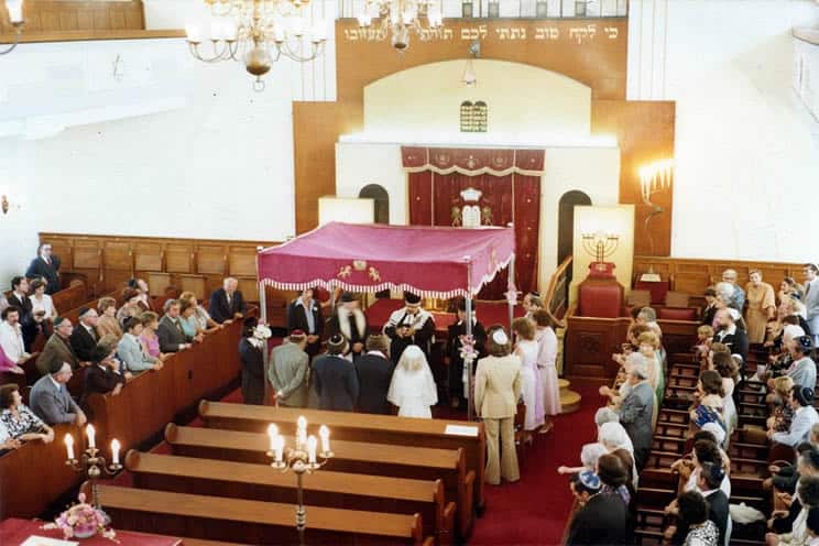 Jewish bride and groom having ceremony under Chuppah