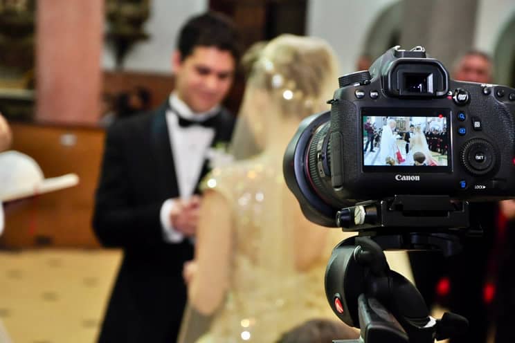 Wedding couple out of focus with camera on tripod in front