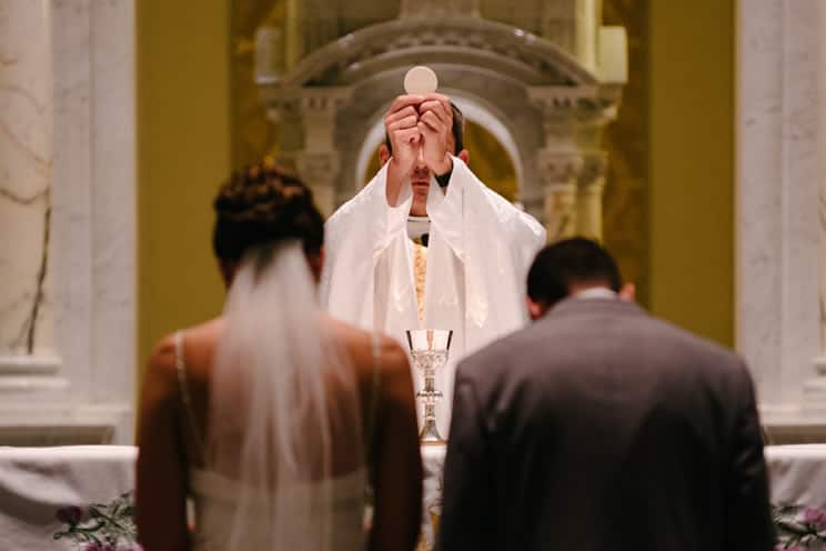 Catholic bride and groom in front of priest at wedding