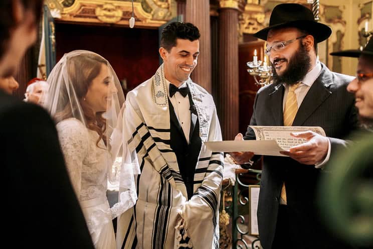 Rabbi reading holy scripture to Jewish couple