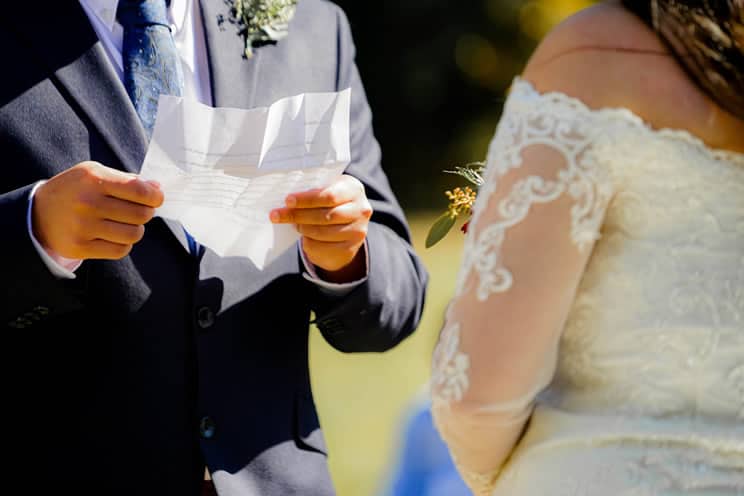Groom reading wedding vows to bride